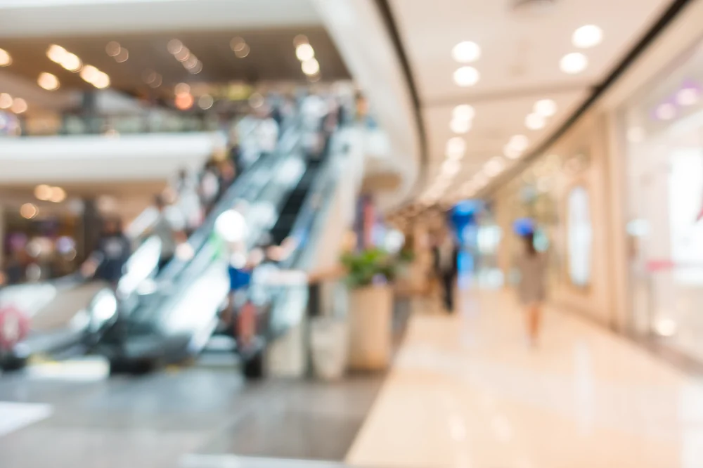 Centro comercial con clientes circulando entre locales, contexto operativo de un ERP para indumentaria multitienda