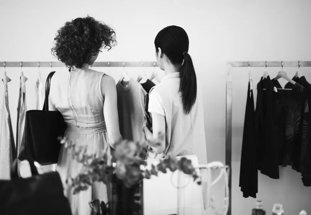 Dos clientas mirando ropa en percheros de una tienda, escena clave de la gestión con ERP para indumentaria