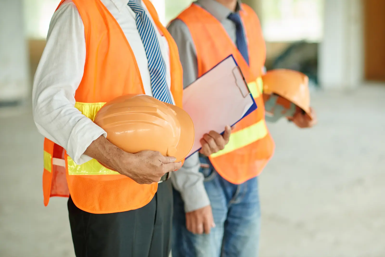 Operarios con equipo de protección personal — chalecos reflectivos y casco — en obra, productos distribuidos por Garimport